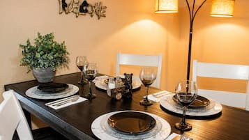 A dining table set with plates, glasses, and cutlery, a potted plant, and a bear figurine.