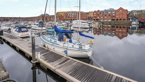 A marina with boats docked, a wooden dock, and red brick buildings in the background.