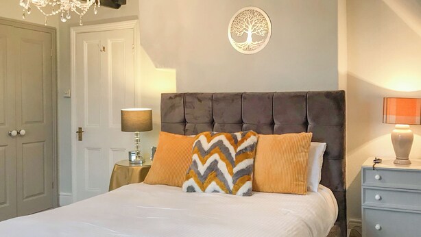 A neatly made bed with two pillows, a bedside table with a lamp, and a wall decoration.