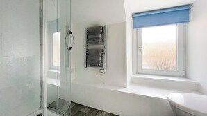 A modern bathroom with a glass shower enclosure, a white toilet, a window with a blue blind, and a towel rack. - Academy Street Cottage (Tain)