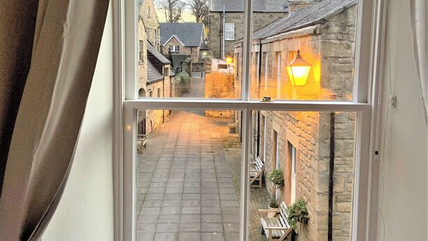 A narrow street with stone buildings, a bench, and a lamp post. - 2 bedroom accommodation in Alnwick (Alnwick)