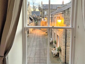 A narrow street with stone buildings, a bench, and a lamp post. - 2 bedroom accommodation in Alnwick (Alnwick)