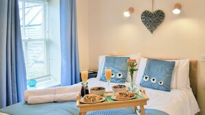 A hotel room with a bed, a breakfast tray, a vase with flowers, and a heart-shaped decoration on the wall. - 2 bedroom accommodation in Alnwick (Alnwick)