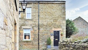 A stone building with a black door marked '6', a small window, and a sign reading 'Quill Corner'. - 2 bedroom accommodation in Alnwick (Alnwick)