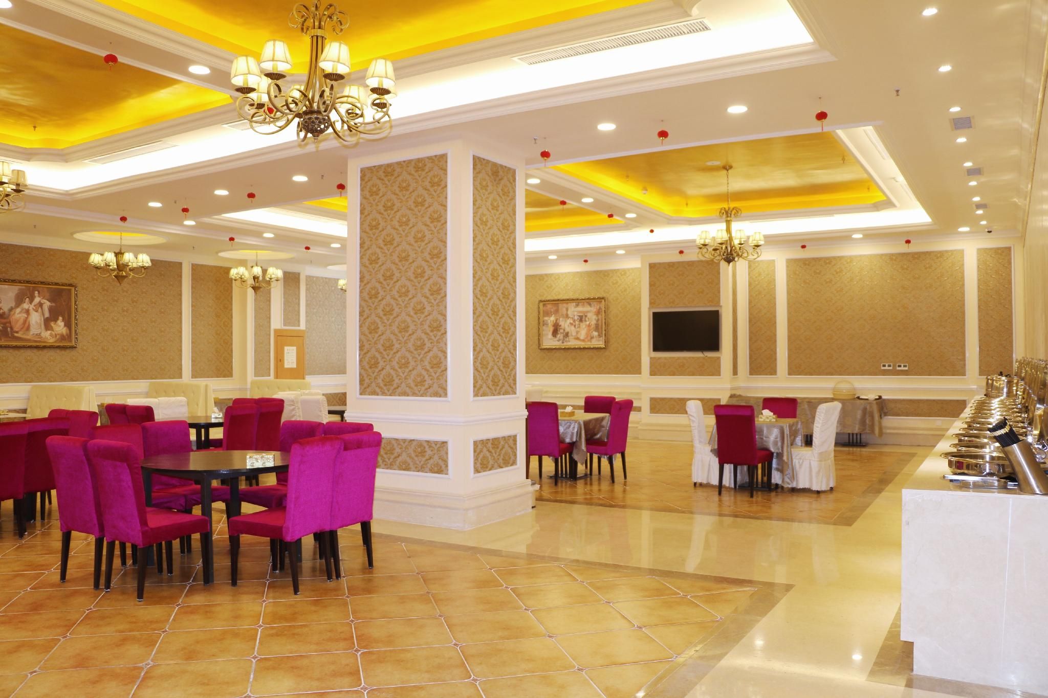 Un comedor de hotel con varias mesas y sillas, un candelabro y una pantalla grande en la pared.