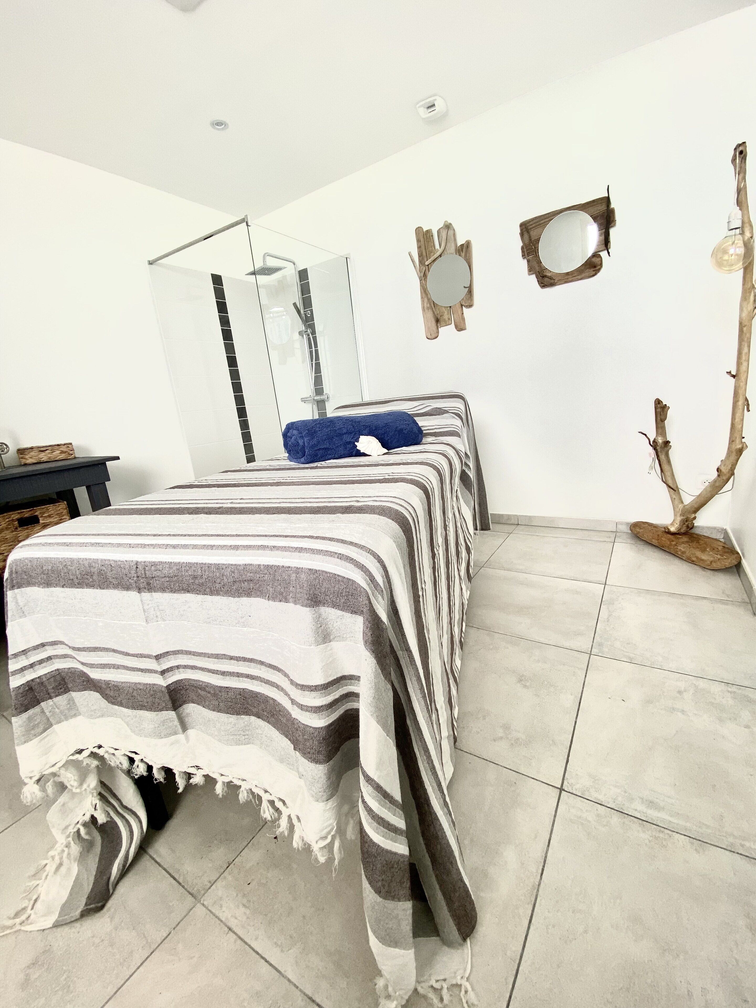 Habitación de hotel con una cama grande, ducha, adorno de rama de madera y un espejo en la pared.