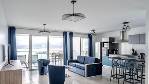 Un salon moderne comprenant un canapé, des fauteuils, un bureau et un coin cuisine avec un bar.