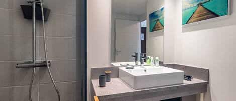 A modern bathroom with a shower, a sink, and a mirror.