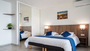 Une chambre moderne avec un grand lit, des lampes de chevet, une tête de lit en bois et un miroir.