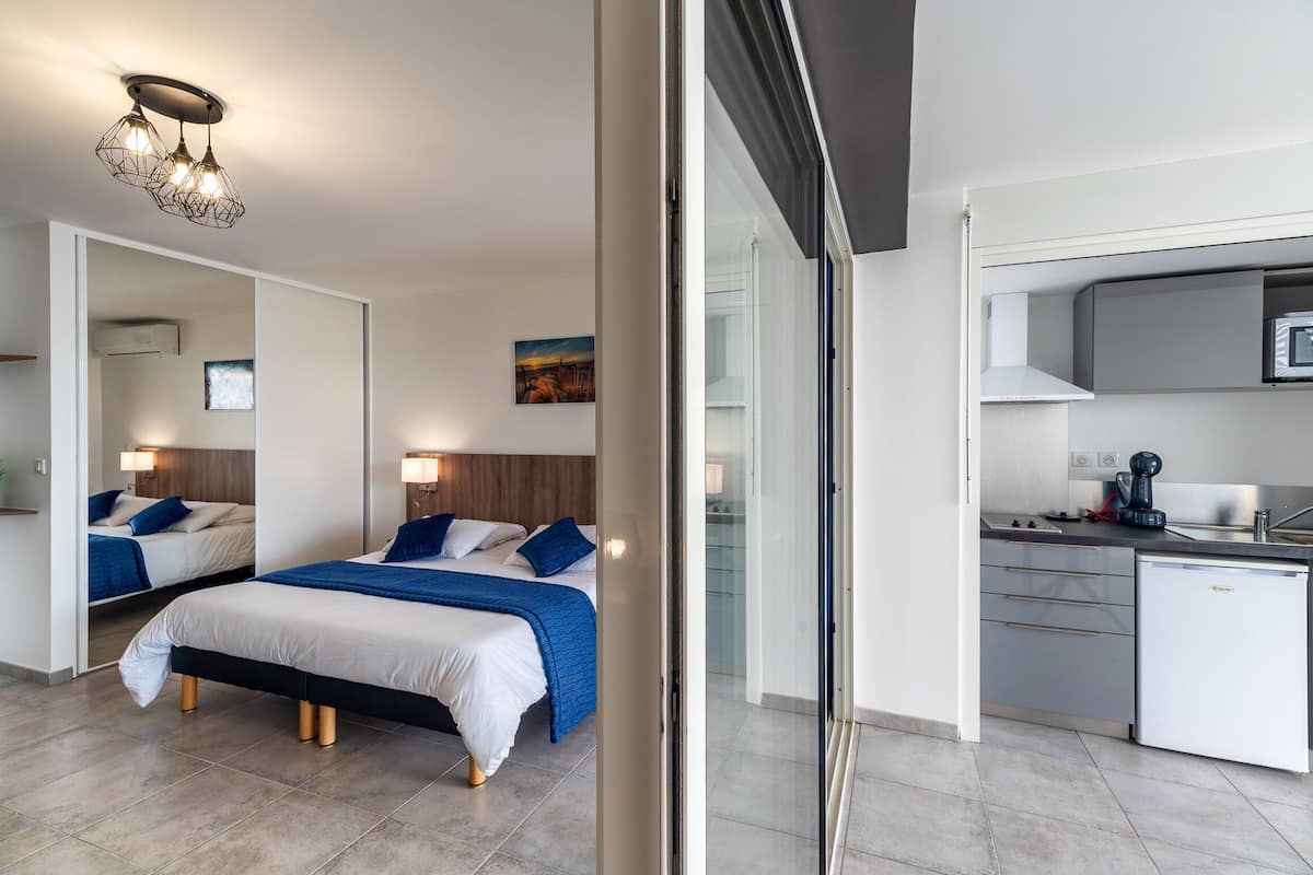 Una habitación de hotel moderna con dos camas, un kitchenette y un baño.