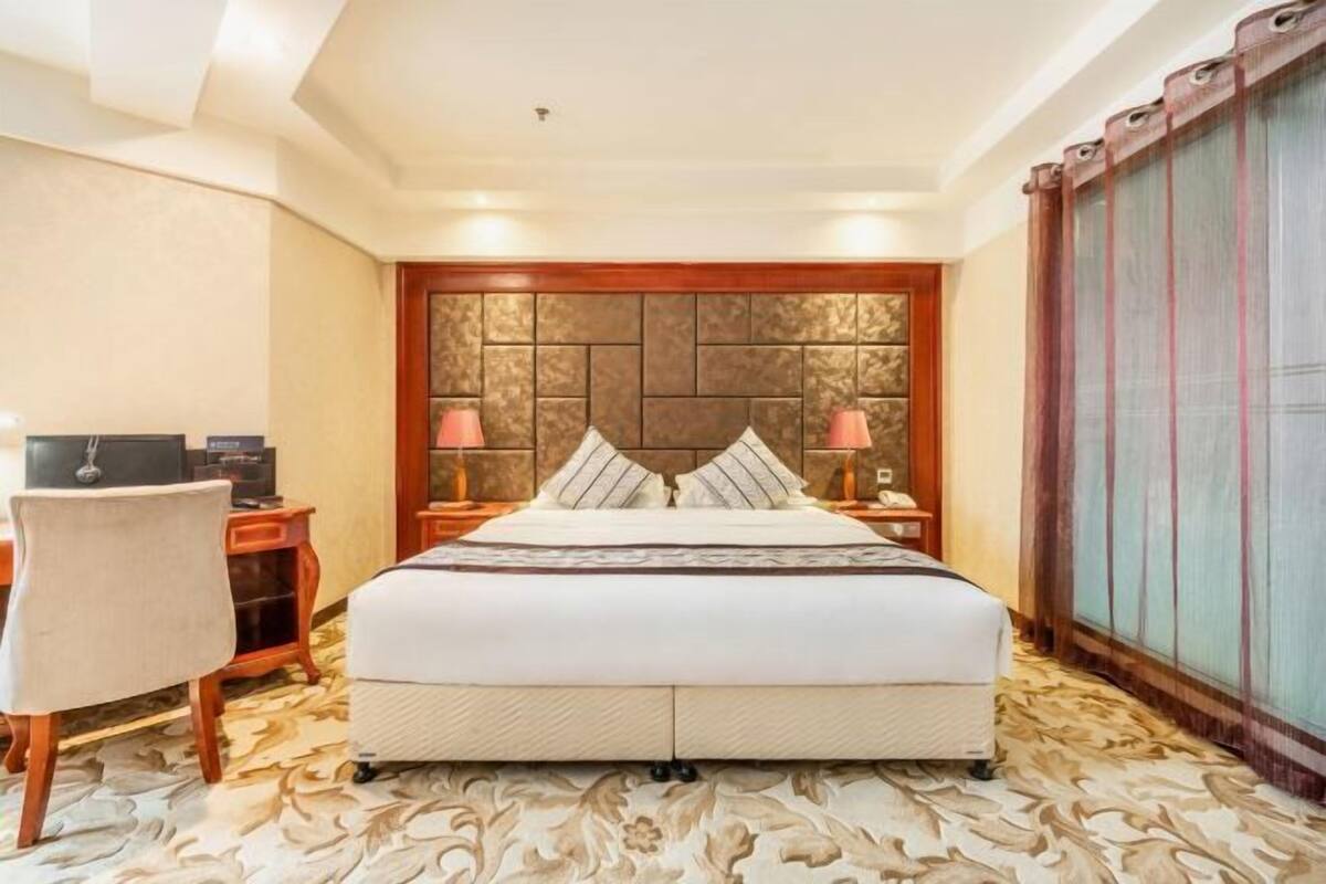 Habitación de hotel con una cama grande, un escritorio con computadora y una silla.