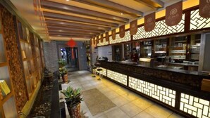 Ein modernes Restaurant mit einer langen Theke, dekorativer Beleuchtung und Topfpflanzen.