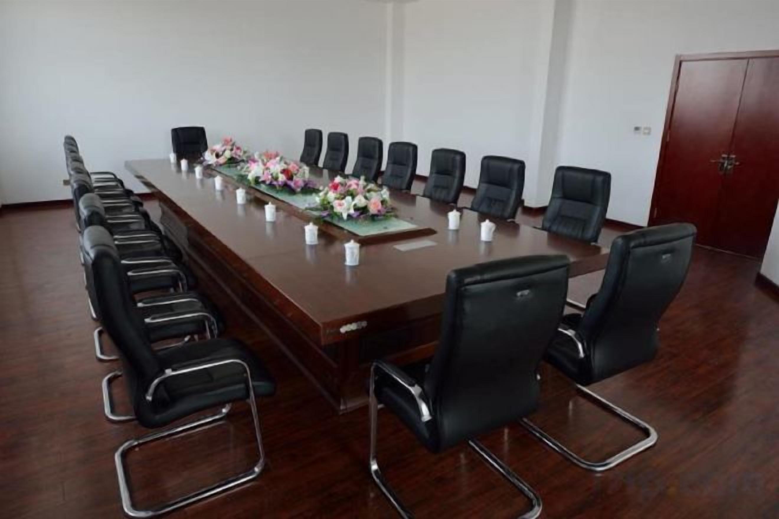 A conference room with a long table, black chairs, and a red door.
