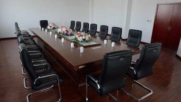 A conference room with a long table, black chairs, and a red door.