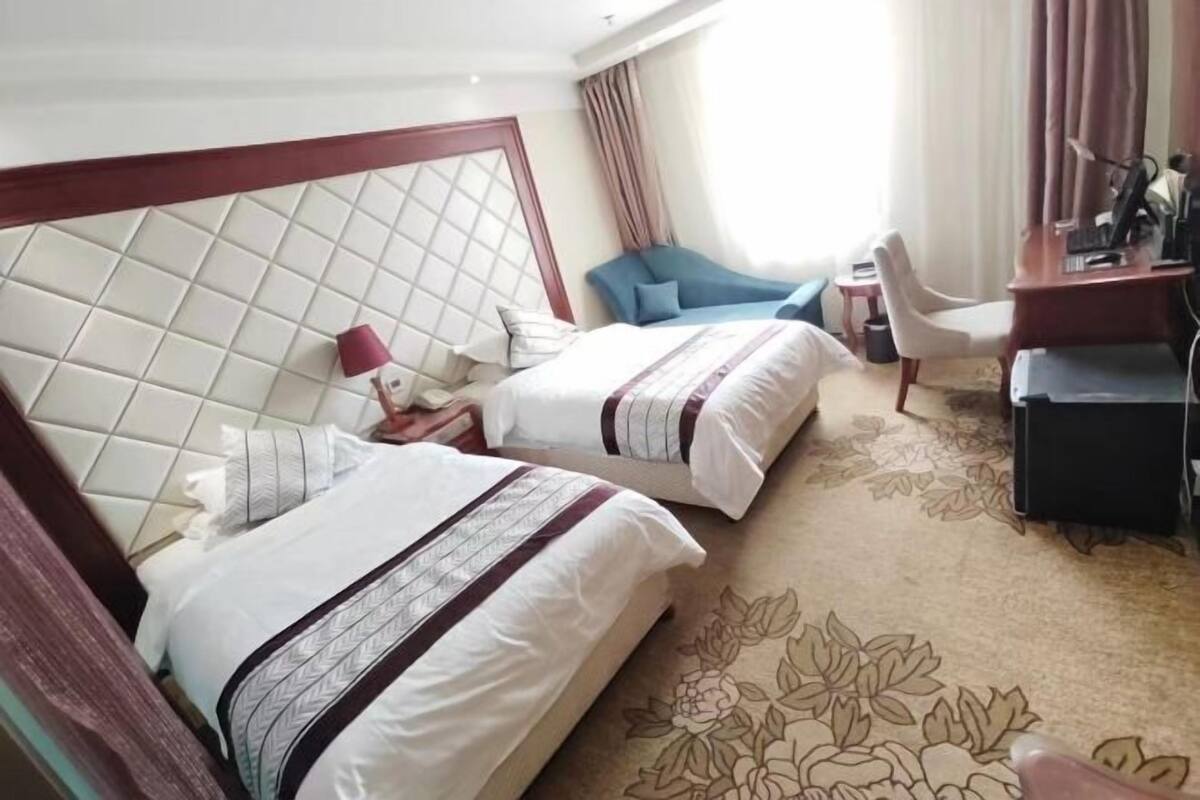 Habitación de hotel con dos camas, un escritorio, una silla y una mesita.