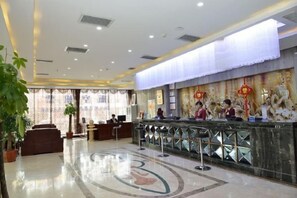 A hotel lobby with a reception desk, seating area, and decorative wall art.