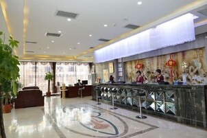 Un vestíbulo de hotel con mostrador de recepción, zona de estar y decoración mural.