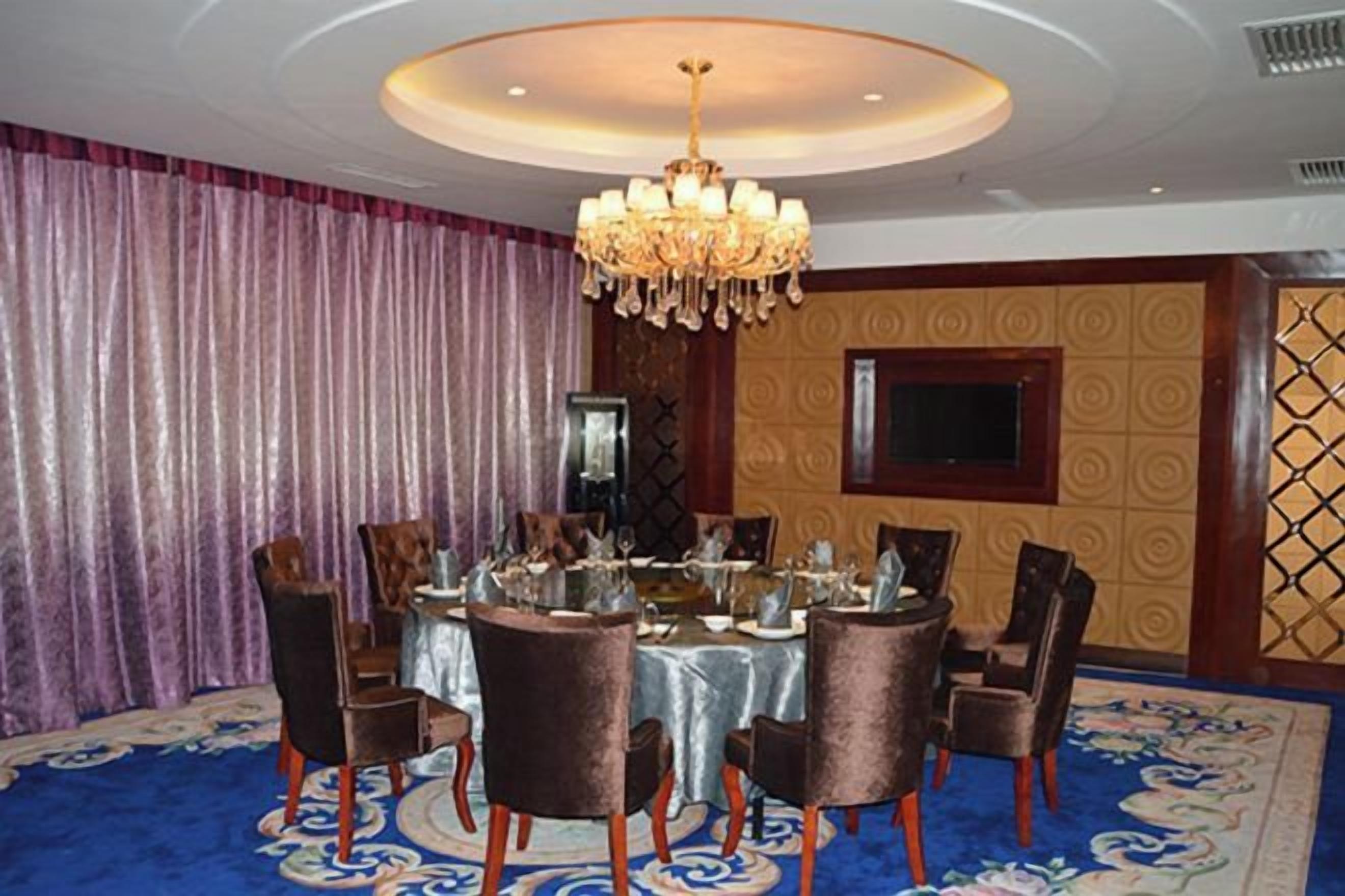 A formal dining room with a round table, chairs, and a chandelier.