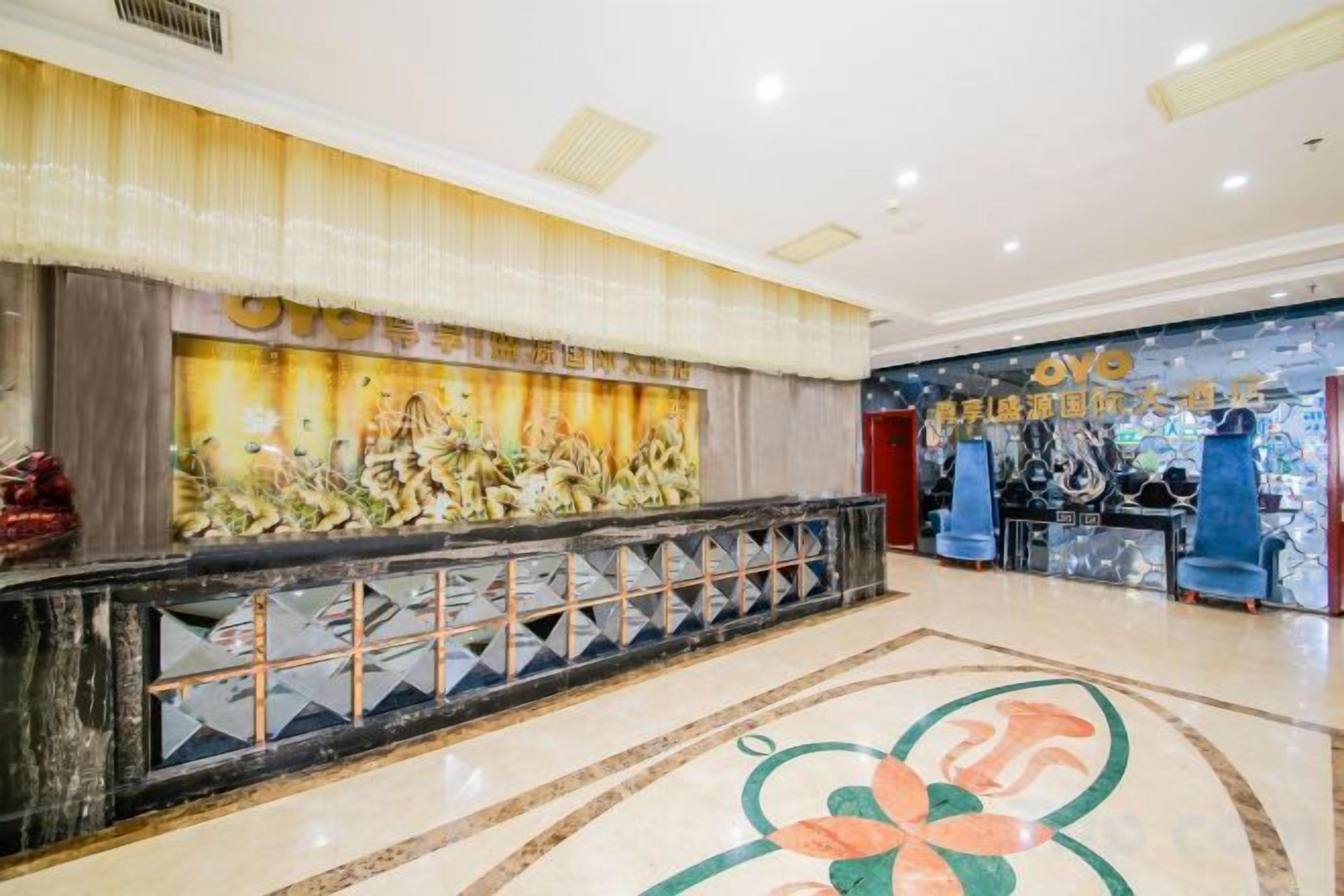 Un vestíbulo de hotel con mostrador de recepción, una pared decorativa y un suelo estampado.