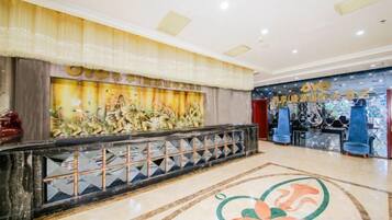 Un vestíbulo de hotel con mostrador de recepción, una pared decorativa y un suelo estampado.