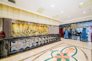 Eine Hotelhalle mit einer Rezeption, einer dekorativen Wand und einem gemusterten Boden.