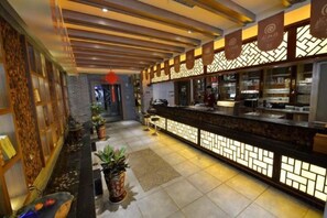 Eine Hotelhalle mit Empfangsschalter, Blumentöpfen und einem strukturierten Wanddesign.