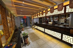 Un vestíbulo de hotel con mostrador de recepción, plantas en macetas y un diseño de pared con motivos.