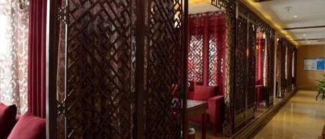 A corridor with a patterned wooden partition, seating areas, and a clean, tiled floor.