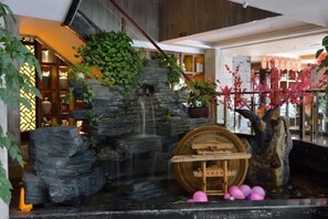 A lobby with a water feature, wooden barrel, and decorative plants. - Qin Hai International Hotel (Baiyin)