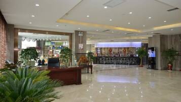 A spacious lobby with a reception desk, seating area, and a large digital screen.