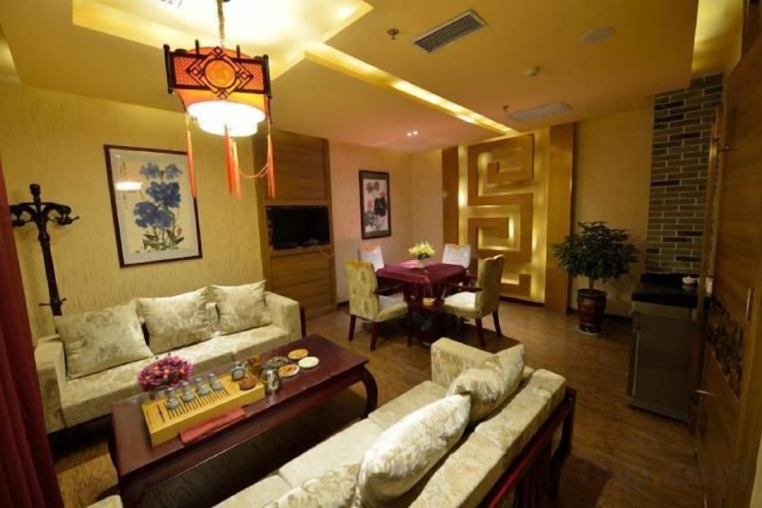 A living room with a sofa, a coffee table, a TV, and a dining area with a table and chairs.