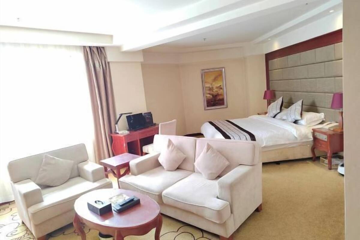 Una habitación de hotel con cama, sofá, escritorio y televisión.