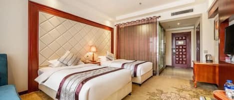 A hotel room with two beds, a desk, a chair, and a television.