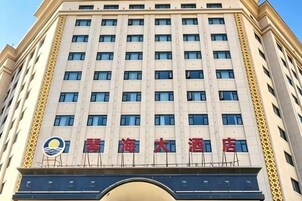 Un edificio de hotel de varios pisos con una entrada destacada y un logotipo sobre el nombre.