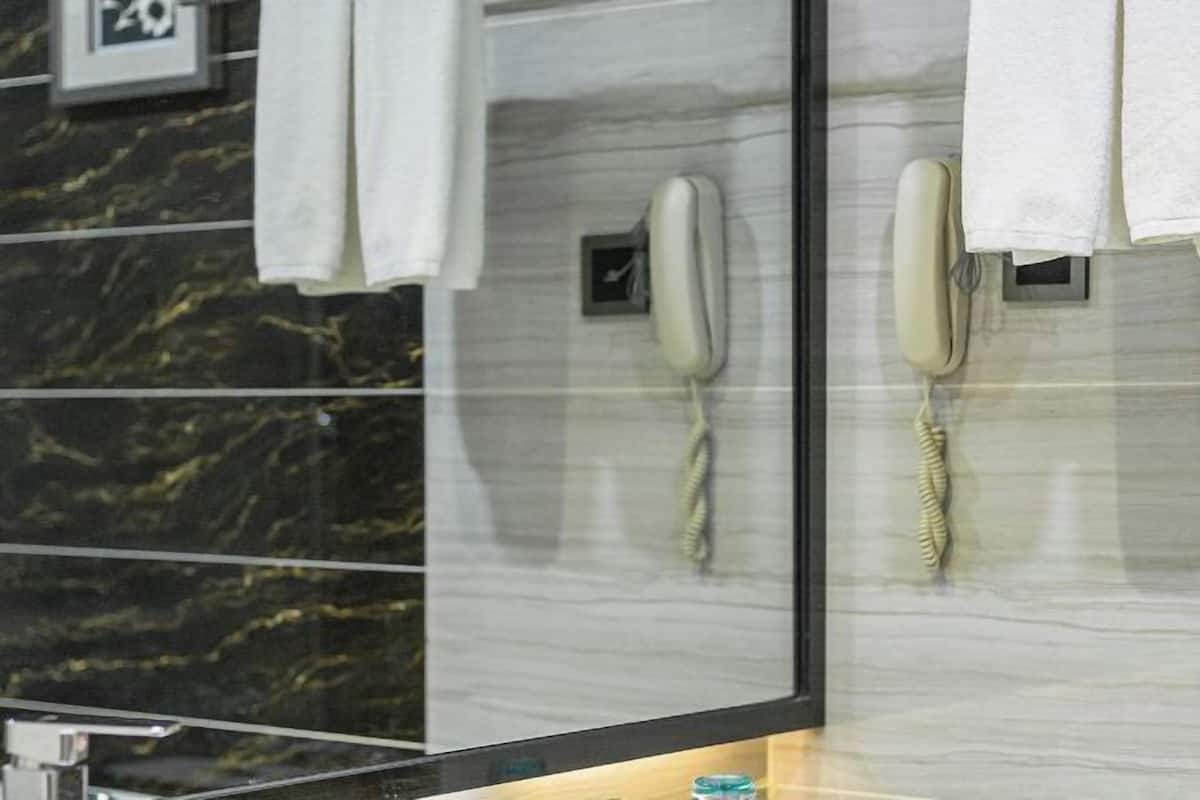 A hotel room with a marble wall, two phones, and a towel rack.