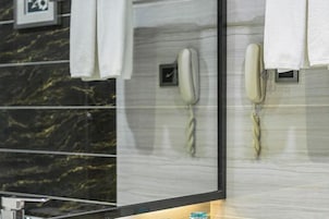 Habitación de hotel con pared de mármol, dos teléfonos y un perchero.