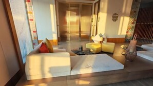 A modern hotel lobby with a sofa area, a wooden floor, and a sliding glass door leading to another room. - Time Platinum (Ziyun)