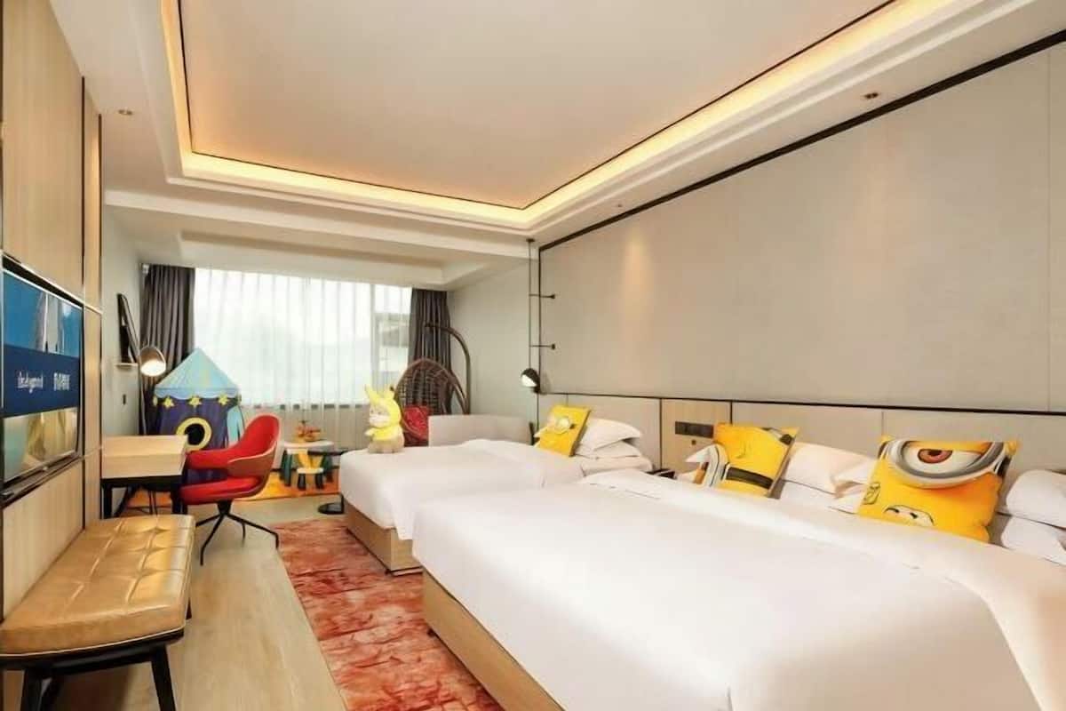 A hotel room with two beds, a desk, a chair, and a TV.