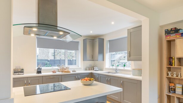 A modern kitchen with a large island, bar stools, a built-in oven, and a window with a view of the outside.