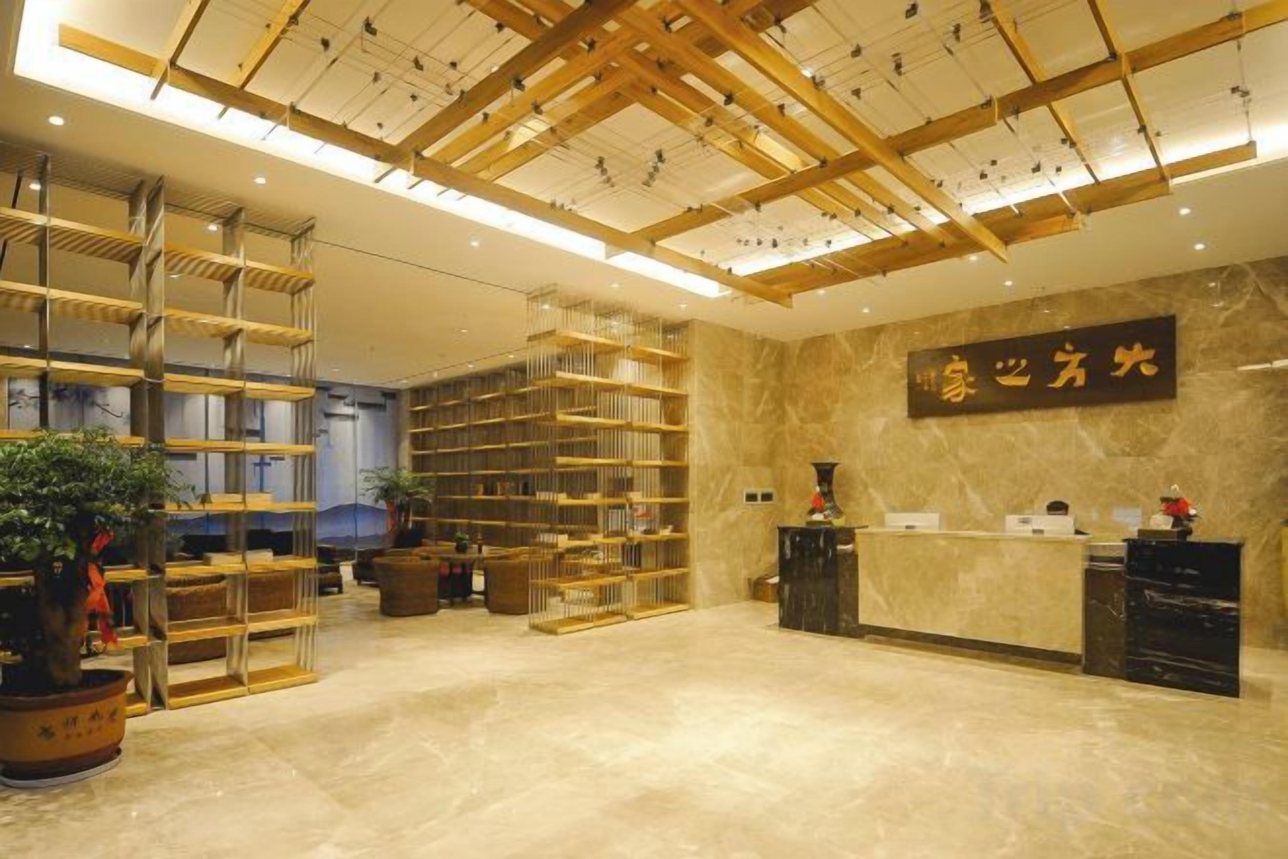 Un vestíbulo de hotel con mostrador de recepción, una amplia estantería de madera y una planta en maceta.