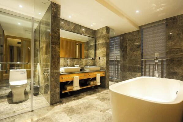 A modern bathroom with a freestanding bathtub, a double sink vanity, a large mirror, and a glass-enclosed shower area. - Deepness Hotel (Qiubei)