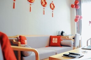 A modern living room with a sofa, red cushions, and a coffee table. - Deepness Hotel (Qiubei)