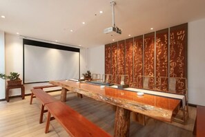 A conference room with a long table, benches, and a projector. - Deepness Hotel (Qiubei)