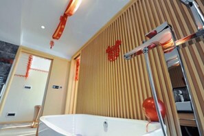 A modern bathroom with a freestanding bathtub, a wooden slatted wall, and a red decorative element. - Deepness Hotel (Qiubei)