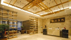 Eine moderne Hotelhalle mit einer Rezeption, Bücherregalen und einer Holzbalkenkonstruktion an der Decke.
