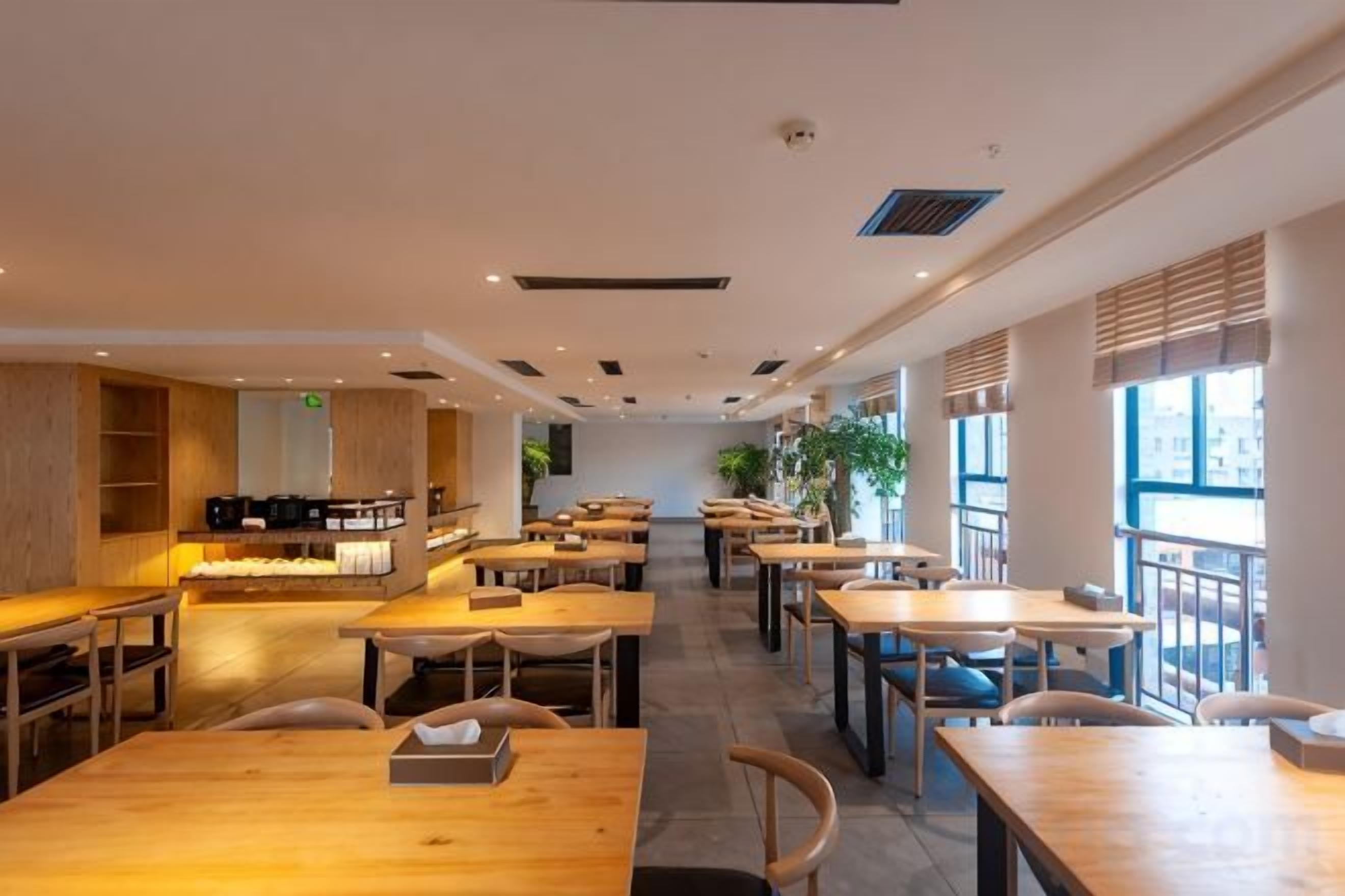 A spacious cafe with multiple tables and chairs, a coffee bar, and large windows allowing natural light.