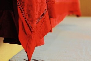 Primer plano de un tejido rojo con un diseño de encaje, probablemente parte de un mueble o elemento decorativo.