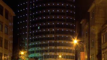 A multi-story hotel with a curved facade, illuminated windows, and a prominent sign at the top.