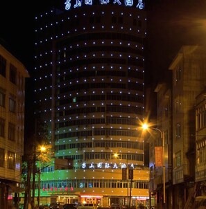 A multi-story hotel with a curved facade, illuminated windows, and a prominent sign at the top. - Rongshui Miaoshan International Hotel (Liuzhou)