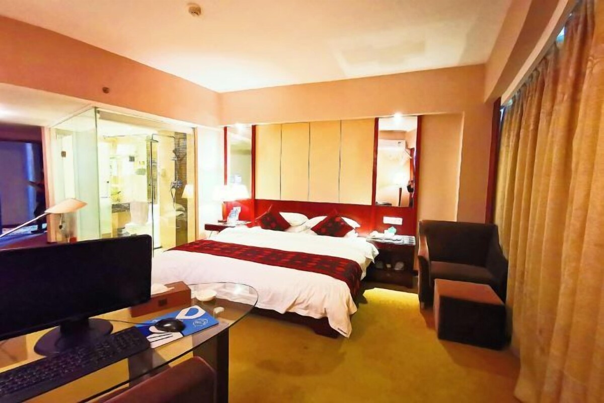 Une chambre d’hôtel comprenant un lit, un bureau avec un ordinateur, une chaise et une table de chevet.